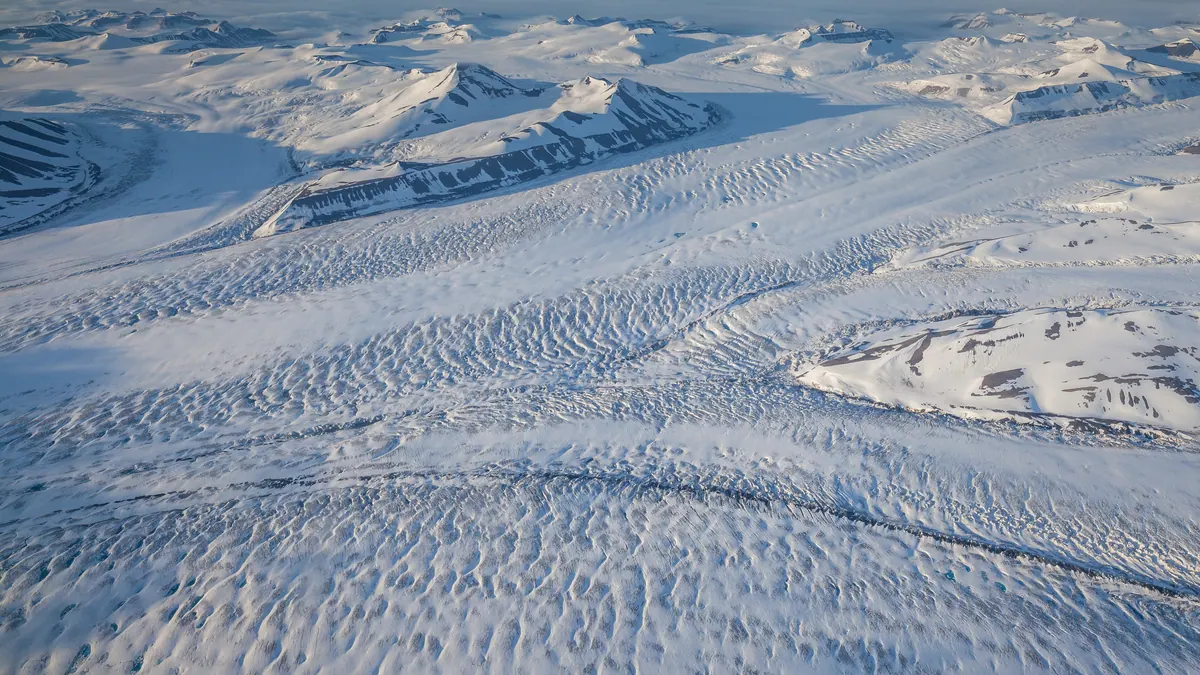 Nathorst glacier in Svalbard lit by the low midnight sun over a calm fjord