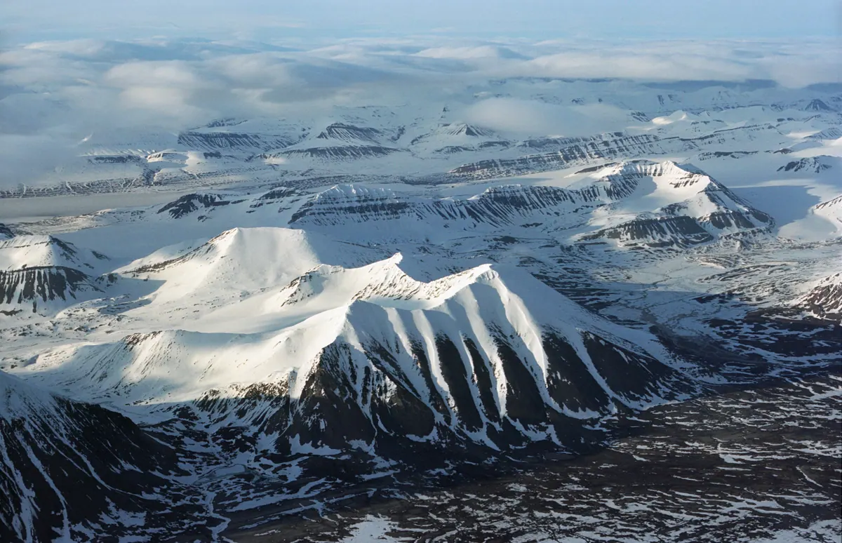 Snow-streaked mountains above a fjord in Spitsbergen, seen on an Arctic expedition cruise